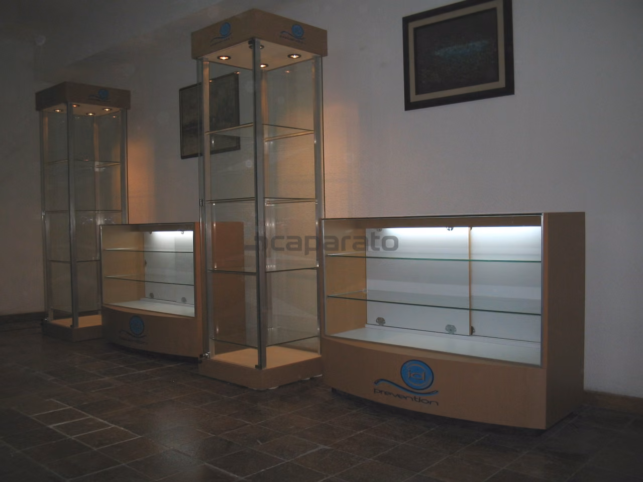 Tres vitrinas de vidrio con iluminación interior y logotipo en la base