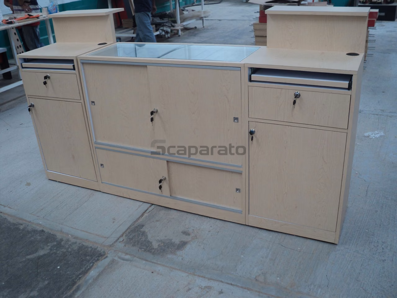 Mostrador de madera clara con vitrina de vidrio y módulos de cajones, en taller de fabricación