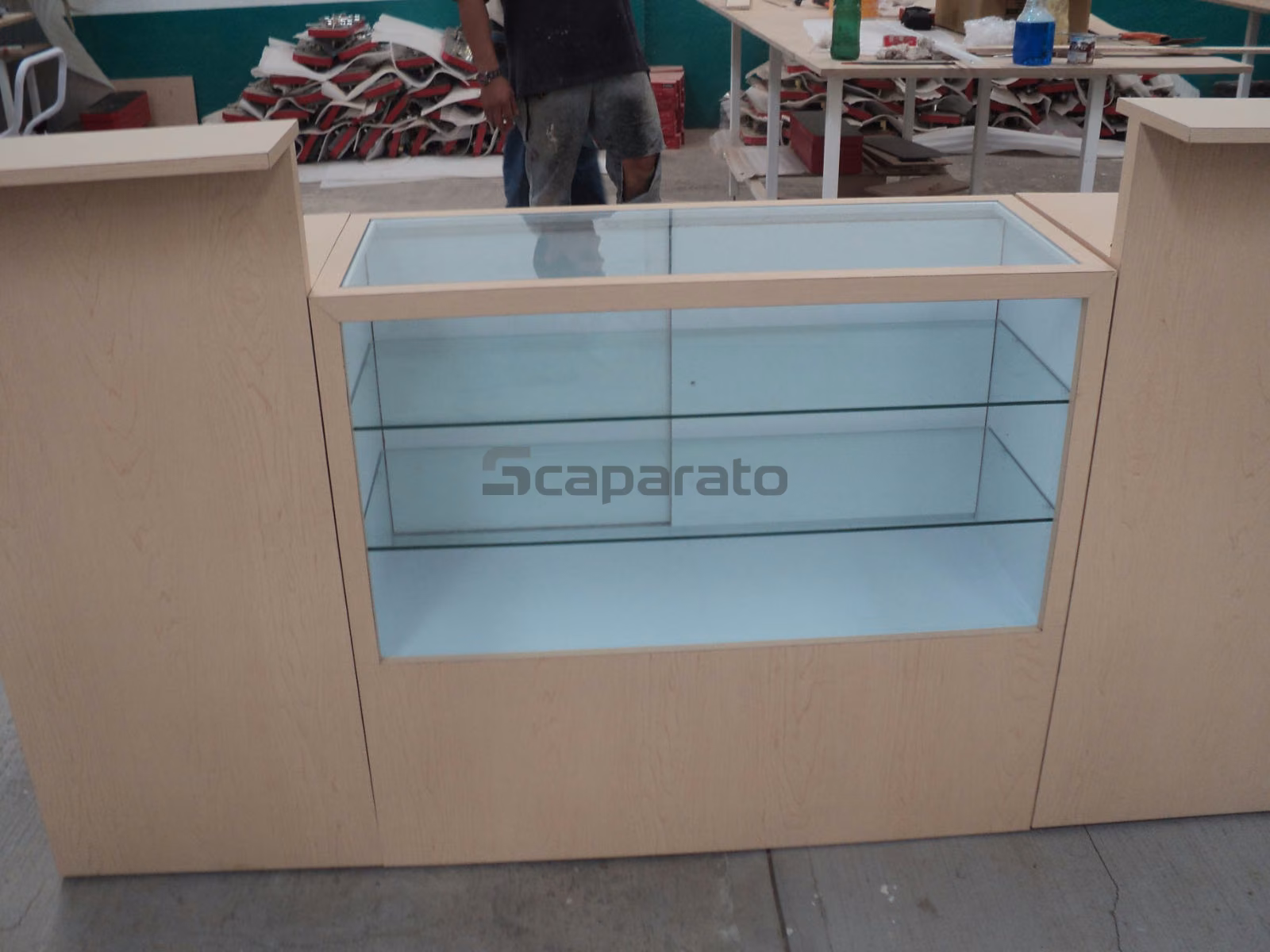 Mostrador de recepción de madera clara con vitrina de vidrio al centro