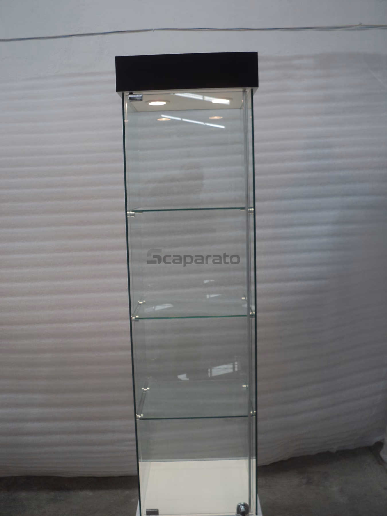 Vitrina de torre de vidrio fabricada por Scaparato, con repisas de vidrio y base cerrada